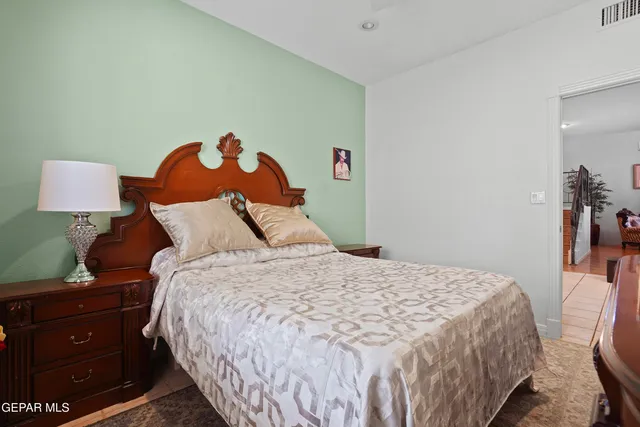 a bedroom with a bed and a lamp on dresser