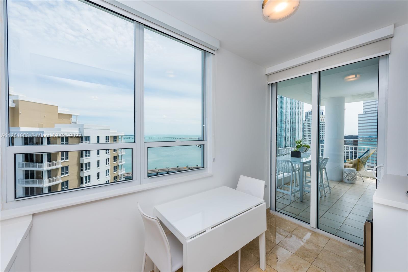 801 Brickell Key Boulevard, Unit 2401 Miami, FL 33131 - Photo 16 of 35 a living room with large windows and a table