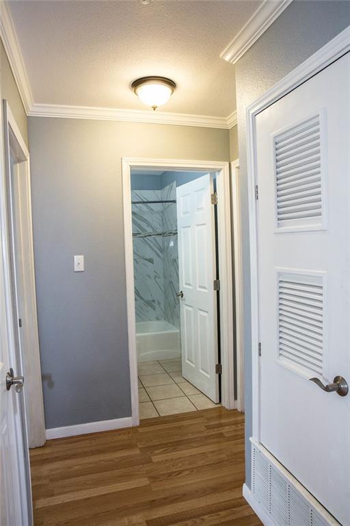4209 Burnet Road, Unit 206 Austin, TX 78756 - Photo 11 of 20 A well-maintained hallway with crown molding provides passage to a tiled bathroom with a tub and shower.