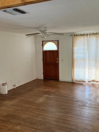 a view of an empty room with wooden floor and closet