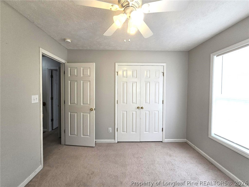5527 Rising Ridge Drive Hope Mills, NC 28348 - Photo 32 of 35 an empty room with windows and chandelier fan