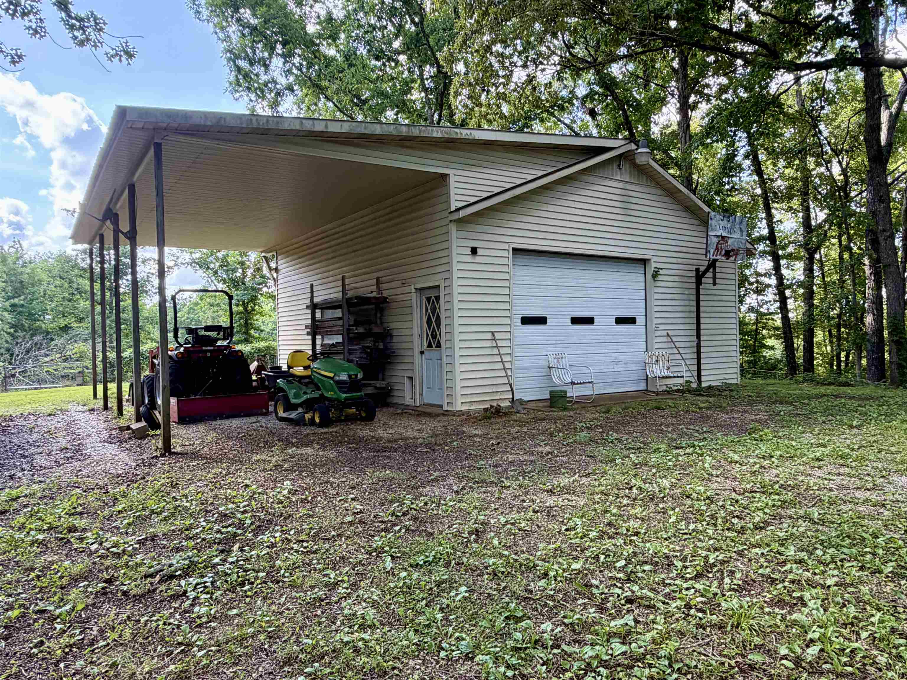 373 Clarence Barham Road Bethel Springs, TN 38315 - Photo 24 of 28 Detached auxiliary structure featuring horizontal siding, an overhead garage door, a covered carport, and a side entry door