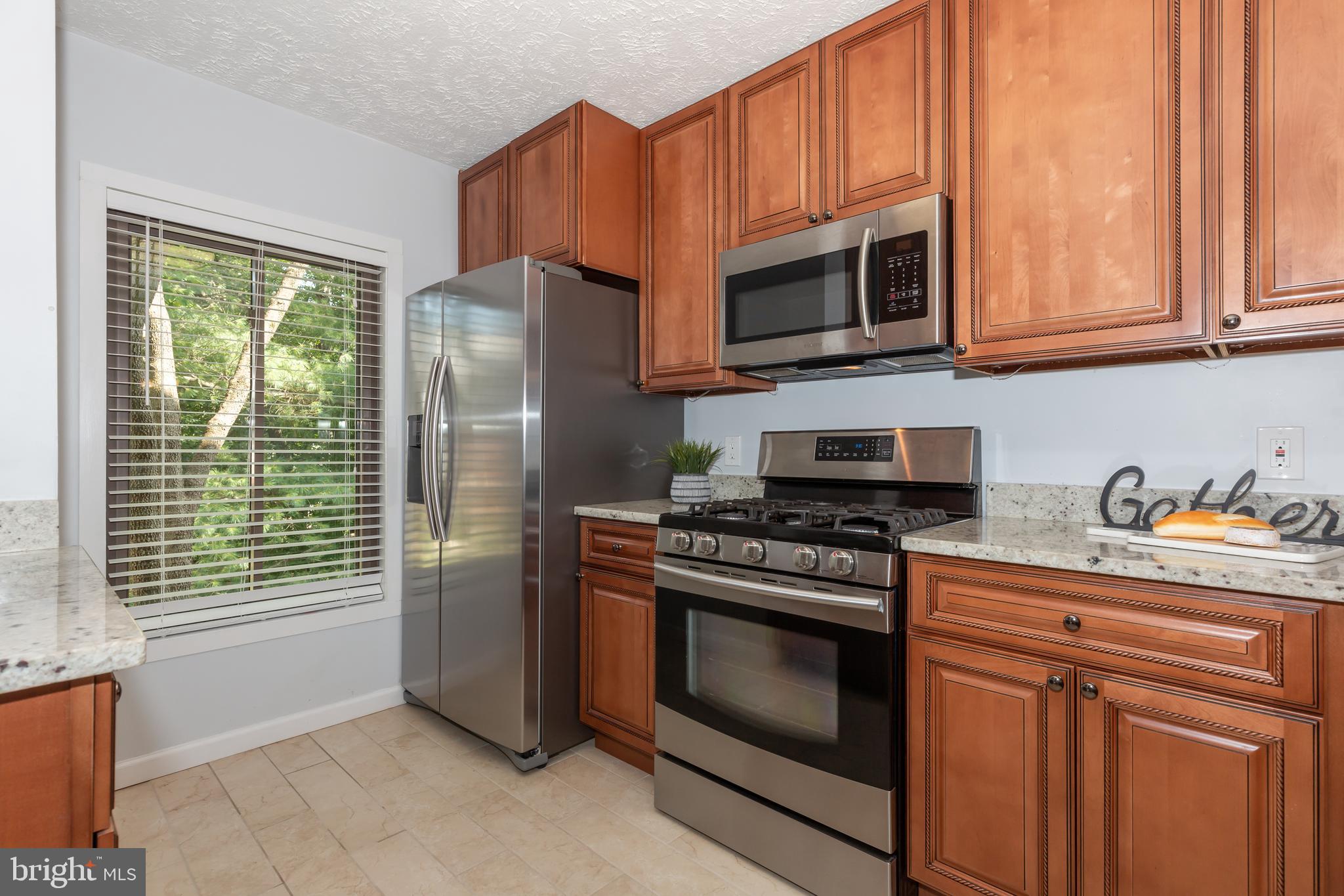 2233 Hunter's Run Drive Reston, VA 20191 - Photo 9 of 50 a kitchen with stainless steel appliances granite countertop a stove a microwave and a refrigerator