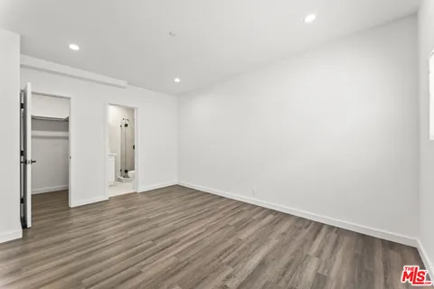 a view of an empty room with wooden floor and closet