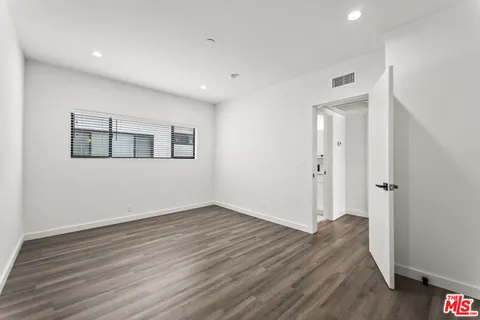 a view of an empty room with wooden floor and closet