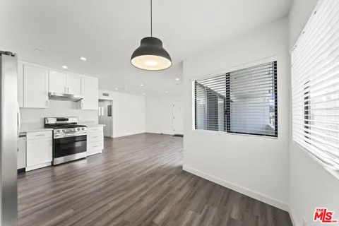 a kitchen with stainless steel appliances a stove a sink a refrigerator wooden floor and cabinets
