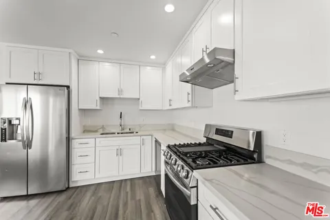 a kitchen with stainless steel appliances granite countertop a stove a sink dishwasher and a refrigerator with wooden floor