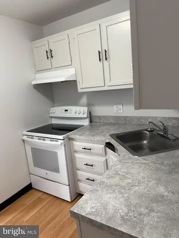 a kitchen with granite countertop a sink a stove and cabinets