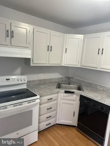 a kitchen with white cabinets and appliances