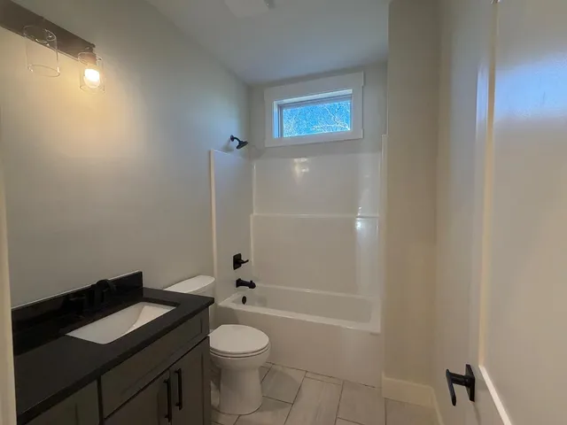 a bathroom with a granite countertop toilet a sink and bathtub