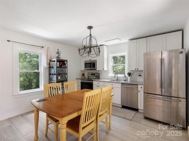 a kitchen with stainless steel appliances granite countertop a refrigerator a stove a dining table and chairs with wooden floor