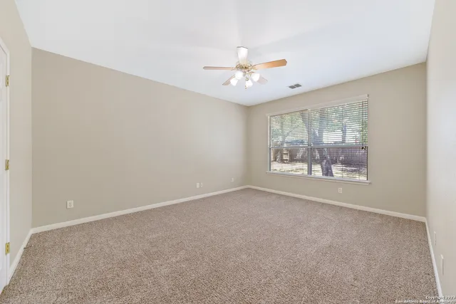 an empty room with a window and a ceiling fan