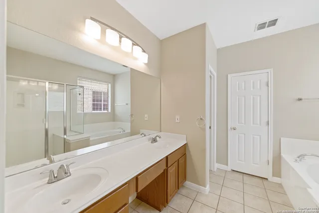 a bathroom with a double vanity sink a mirror and a bathtub