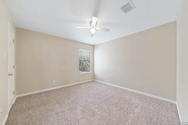 an empty room with a window and a ceiling fan