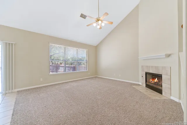 an empty room with windows and fireplace