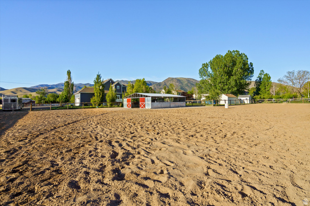 681 Island Road Morgan, UT 84050 - Photo 29 of 49 Expansive equestrian arena featuring a sand surface, a white-fenced perimeter, and a detached barn structure with red-painted doors