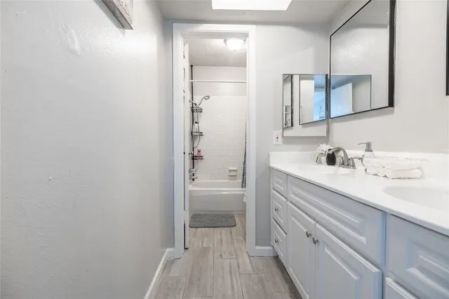 a bathroom with a double vanity sink a mirror and a bathtub