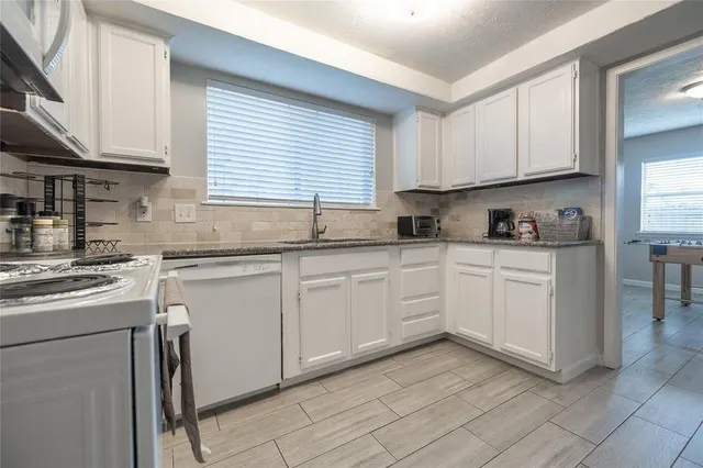 a kitchen with white cabinets sink and appliances