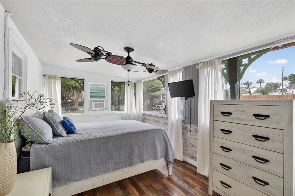 521 Michigan Street Mount Dora, FL 32757 - Photo 11 of 27 a bedroom with a bed a flat screen tv and a large window