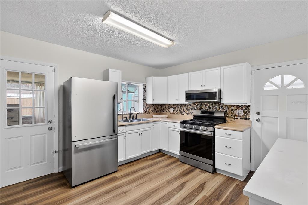 521 Michigan Street Mount Dora, FL 32757 - Photo 6 of 27 a kitchen with white cabinets and stainless steel appliances