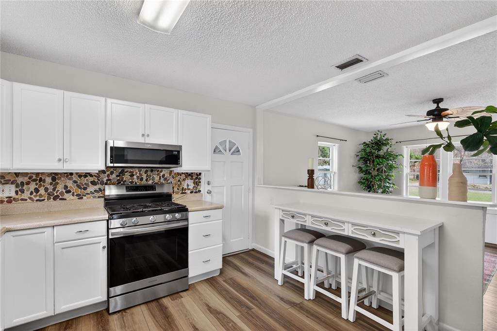 521 Michigan Street Mount Dora, FL 32757 - Photo 8 of 27 a kitchen with stainless steel appliances a stove top oven a sink dishwasher and a refrigerator