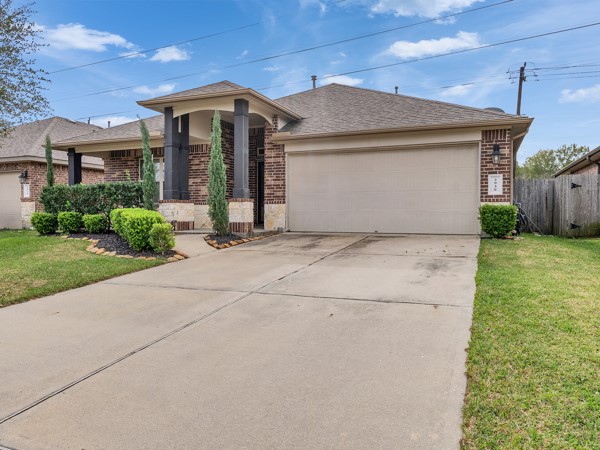 This is a modern, single-story brick home with a two-car garage and well-maintained landscaping. The driveway is spacious, and the exterior features a welcoming front porch.