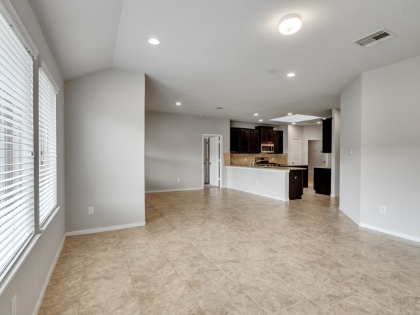 2939 Canadian Goose Lane Baytown, TX 77521 - Photo 15 of 44 This photo showcases a modern kitchen with dark wood cabinets, granite countertops, a tiled backsplash, and stainless steel appliances. The open layout features recessed lighting and a spacious island, perfect for entertaining.
