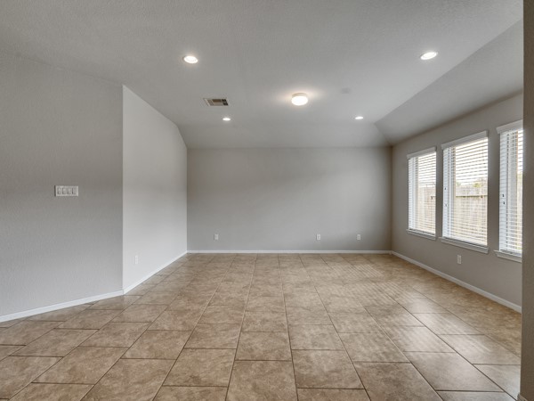 2939 Canadian Goose Lane Baytown, TX 77521 - Photo 15 of 48 This photo showcases an open-concept living area with a spacious kitchen featuring dark cabinetry and stainless steel appliances. The room is well-lit with recessed lighting, and the floor is tiled, providing a clean and modern look.