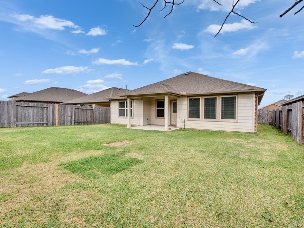 2939 Canadian Goose Lane Baytown, TX 77521 - Photo 32 of 44 This photo shows a single-story home with a spacious fenced backyard and a covered patio, perfect for outdoor activities and relaxation. The exterior features a neutral color scheme and a well-maintained lawn.