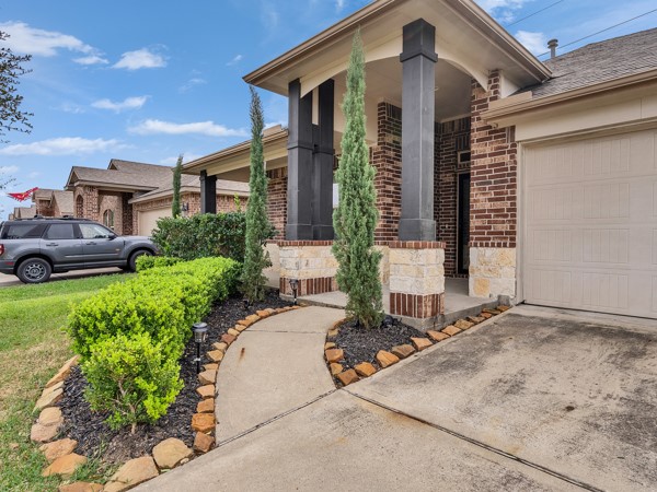 2939 Canadian Goose Lane Baytown, TX 77521 - Photo 9 of 44 This inviting home features a charming brick exterior with a welcoming front porch and neatly landscaped walkway. It has tall, slender trees and well-maintained shrubs lining the path, adding curb appeal. The driveway leads to an attached garage, enhancing convenience.