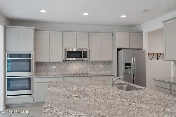 a kitchen with granite countertop a sink a stove and a refrigerator