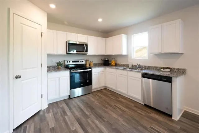 a kitchen with stainless steel appliances granite countertop a stove a sink and a refrigerator