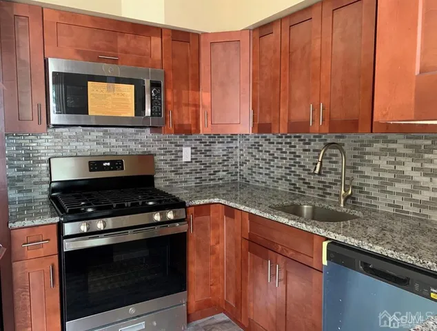 a kitchen with granite countertop stainless steel appliances a stove sink and cabinets