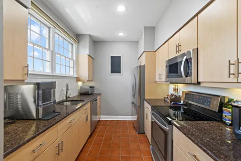 a kitchen with stainless steel appliances granite countertop a sink stove and refrigerator