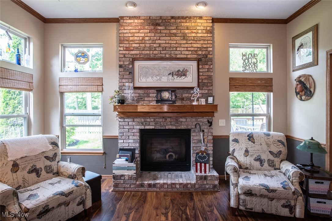 126 Timber Ridge Drive Elyria, OH 44035 - Photo 5 of 49 Living room featuring a brick fireplace, wood finished floors, crown molding, and baseboards