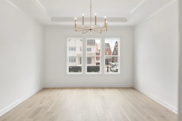 an empty room with a chandelier fan and windows