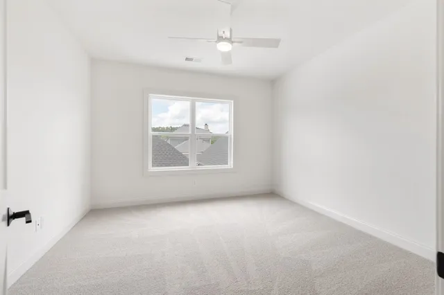 an empty room with windows and fan