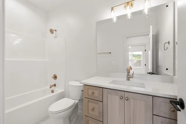 a bathroom with a granite countertop sink a toilet and shower