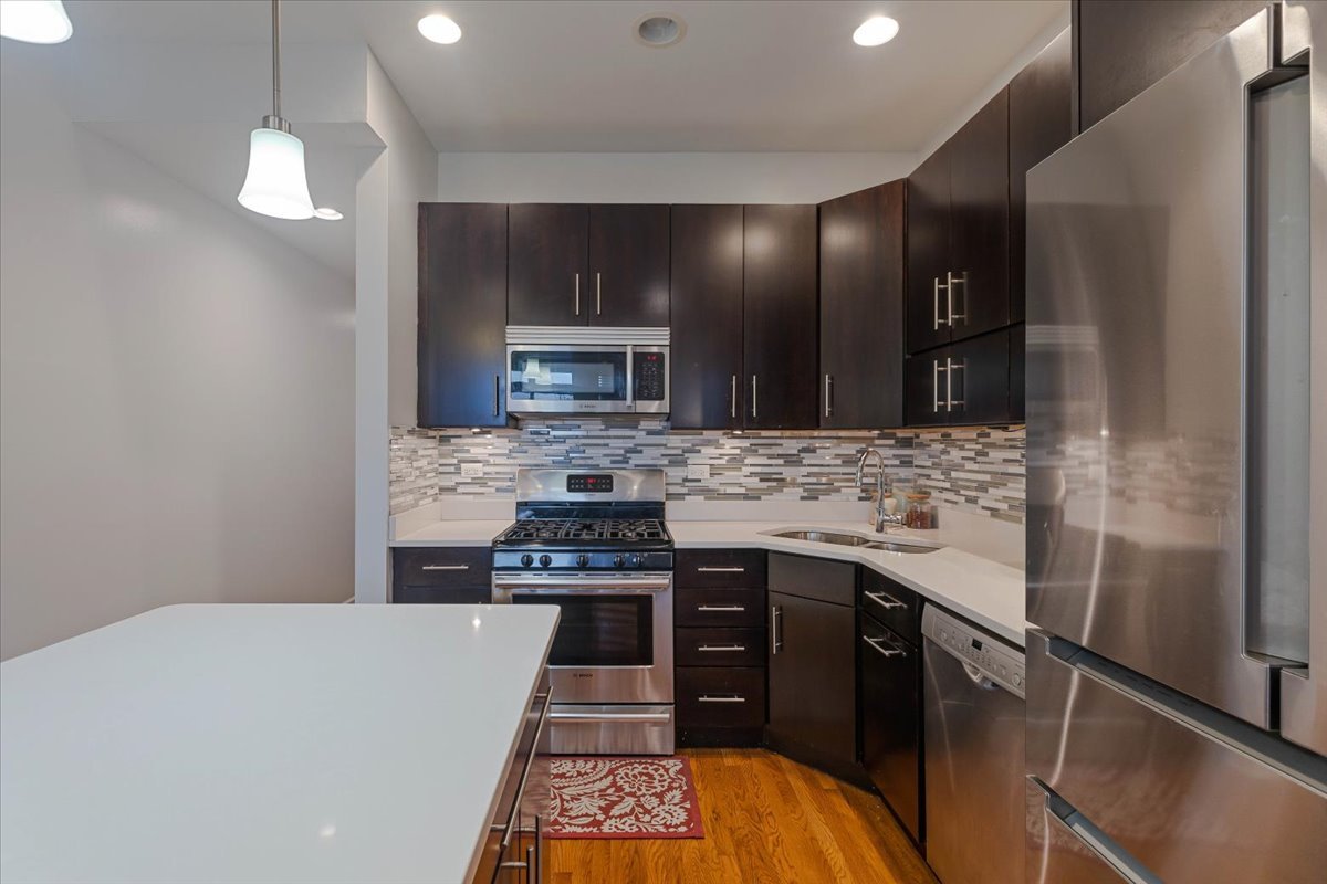 2130 West Rice Street, Unit 4 Chicago, IL 60622 - Photo 15 of 35 a kitchen with stainless steel appliances kitchen island granite countertop a stove a sink and a microwave