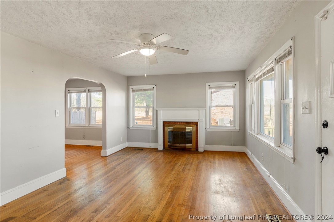 1700 Cedar Creek Road Fayetteville, NC 28312 - Photo 11 of 21 an empty room with windows fireplace and wooden floor
