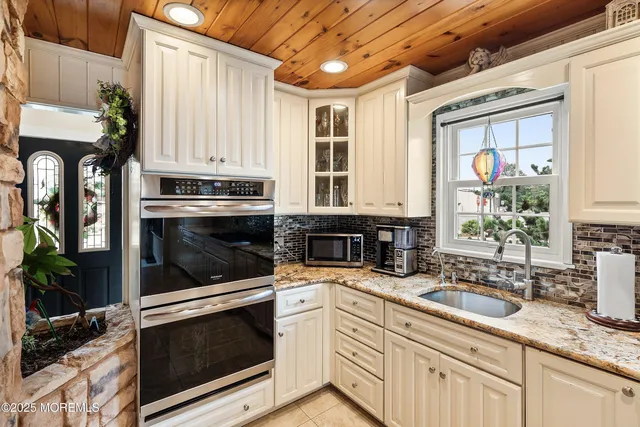 a kitchen with granite countertop white cabinets stainless steel appliances and a potted plant