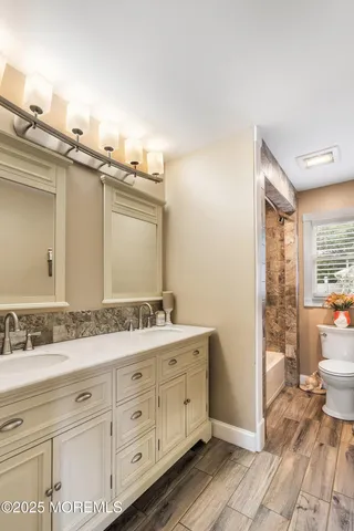 a bathroom with a double vanity sink a mirror and a toilet