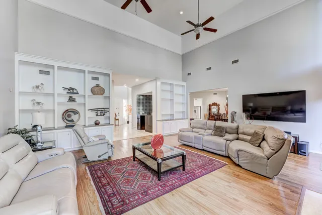 a living room with furniture large window and wooden floor