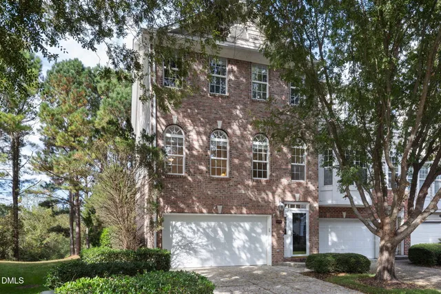 a front view of a house with a yard and large trees