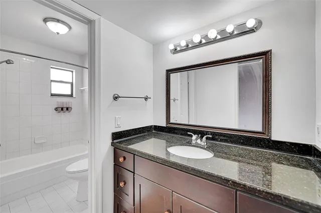 a bathroom with a granite countertop sink a light fixture and a mirror