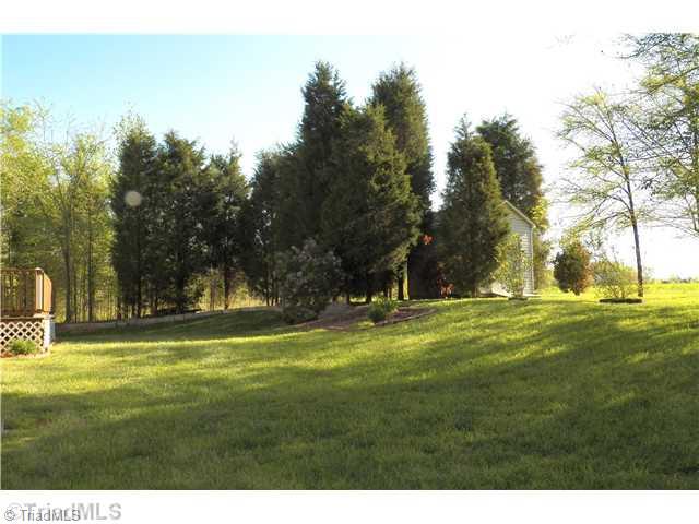485 Riverview Rd Extension Lexington, NC 27292 - Photo 2 of 16 Exterior Back. View of backyard and shed behind trees. Yard backs up to farm land - Deer often seen grazing in the fields Plenty of room in the back yard to put in a pool next to the back deck. Lots of privacy!