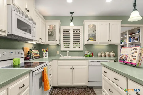 a kitchen with stainless steel appliances a white cabinets and a stove top oven