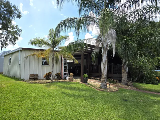 a view of a white house with a yard and sitting area