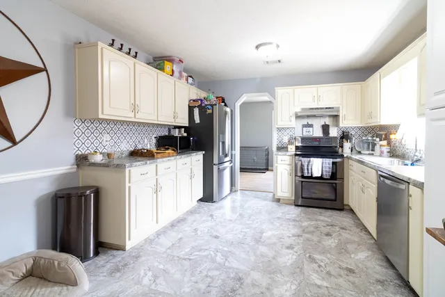a kitchen with granite countertop a refrigerator sink stove and cabinets