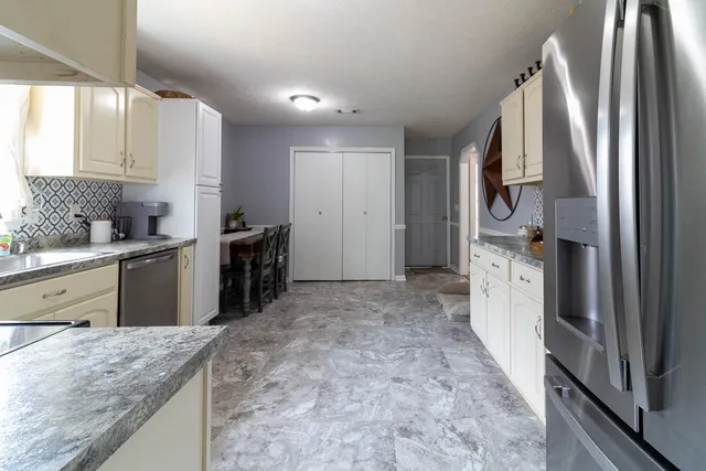 a kitchen with stainless steel appliances granite countertop a refrigerator a stove and a sink